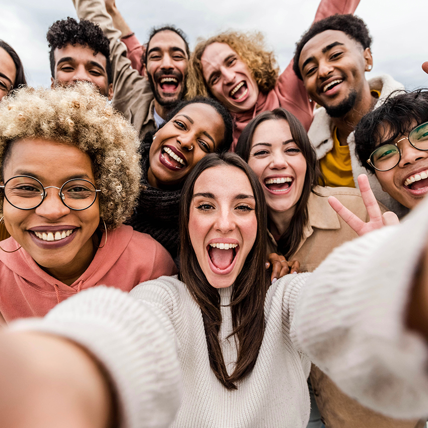 Multiracial friends taking big group selfie shot smiling at camera—Laughing young people standing outdoor and having fun